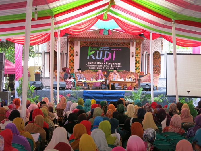Een volle zaal met bijna uitsluitend gesluierde vrouwen luistert naar vijf sprekers van het het Indonesische Congres van Vrouwelijke Oelama (Kongres Ulama Perempun Indonesia) van 2017. Drie van de sprekers zijn vrouw, twee zijn man.
