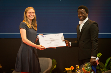 De voorzitter van het Leids Universitair Studentenplatform geeft Ayo Adedokun de prijs