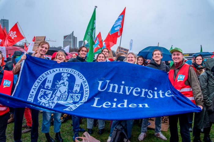 Actievoerders staan op het Malieveld in Den Haag met een spanddoek van de Universiteit Leiden