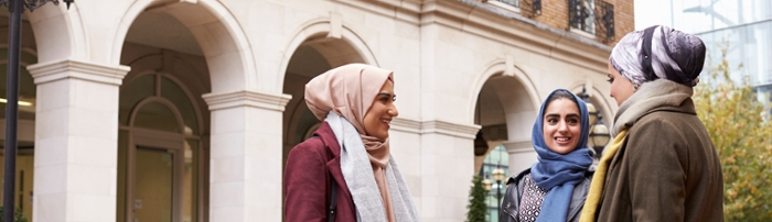 Drie jonge vrouwen met een hidjab praten en lachen