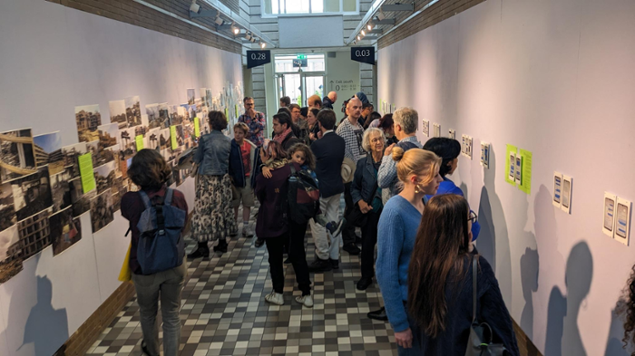 Bezoekers van de tentoonstelling ‘Picturing Scholasticide’ in een gang aan de Universiteit Leiden.