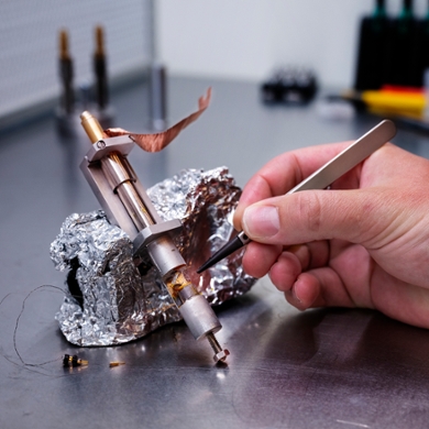 Close-up van het deel waarin de kleine magneet zweeft; Uitenbroek bereidt zijn volgende metingen voor door kabels en sensoren aan te sluiten.