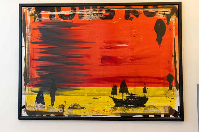 het kunstwerk hong kong bay, veel rood en geel met een bootje op de voorgrond in zwart